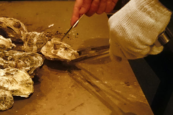 かき焼き てっぱんで牡蠣の殻を剥がす